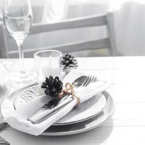 Place table setting on white table with Christmas decor elements. Silver color